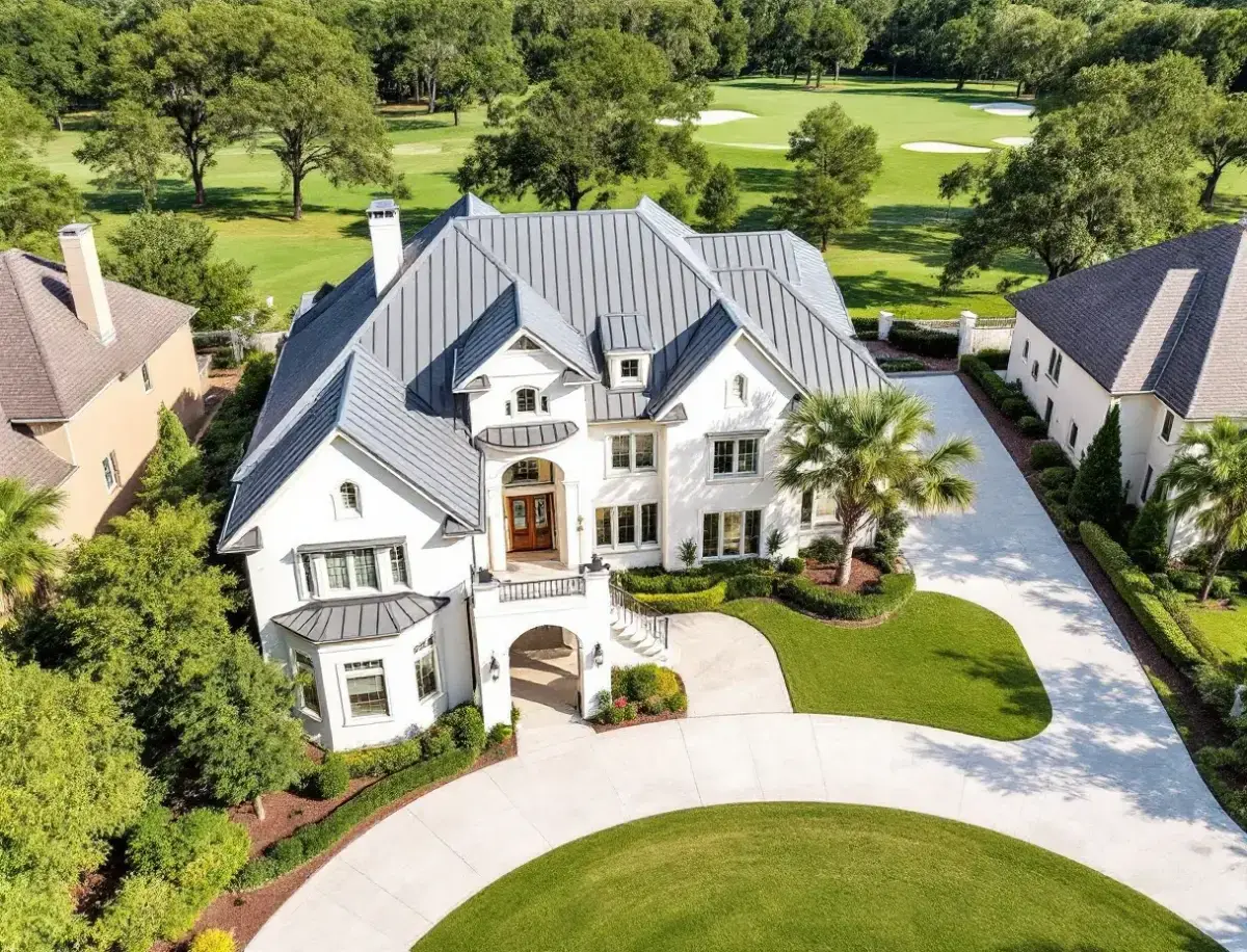 Limestone-and-stucco custom home with a tile roof on a manicured lot beside a golf fairway, live oaks at dusk